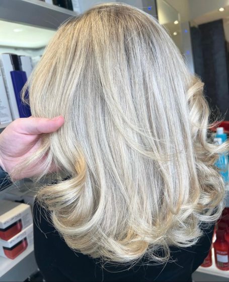 Close-up of wavy, blonde hair styled elegantly from the back.