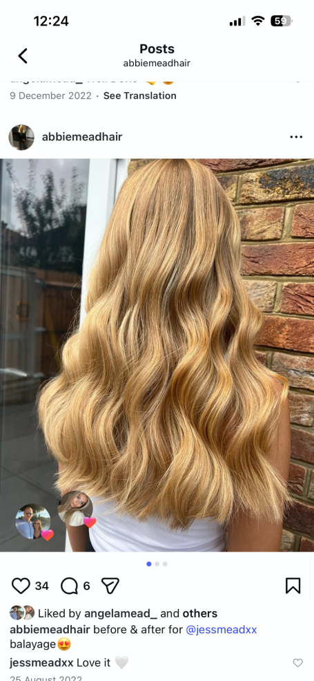 Long, wavy blonde hair cascading down against a brick wall background.
