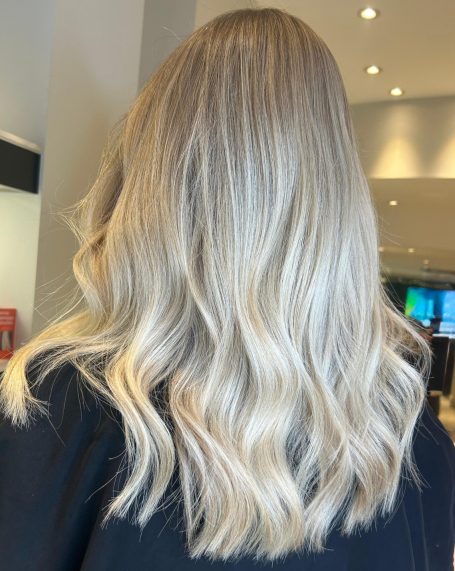 Long, wavy blonde hair viewed from behind, with soft highlights and a smooth finish.