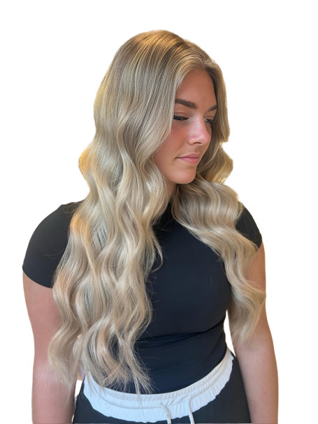 Woman with long wavy blonde hair wearing a black top, looking to the side.