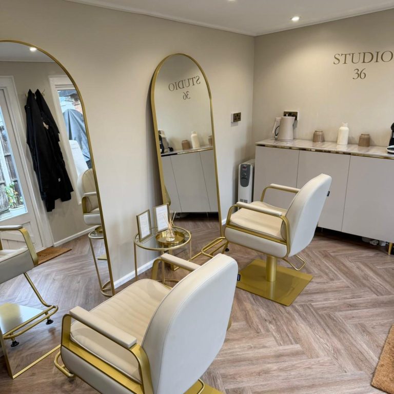 A person receives a hair wash at a salon, with water flowing and a stylist's hands visible.